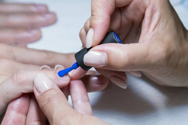 Hermoso proceso de manicura. El esmalte de uñas que se aplica a la mano, el esmalte es de color azul. de cerca — Foto de Stock