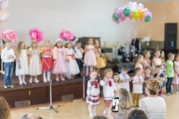Kinderfest in der Grundschule. Kleine Kinder auf der Bühne im Kindergarten treten vor Eltern auf. verschwommen. Zurück zur Schule — Stockfoto