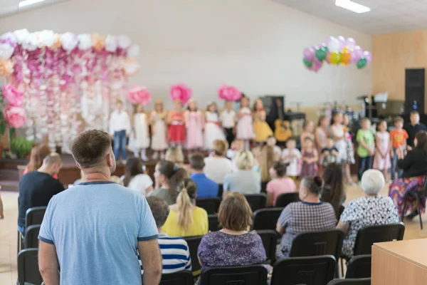 Children\'s party in primary school. Young children on stage in kindergarten appear in front parents. blurry. back to school