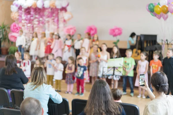 Impreza dziecięca w szkole podstawowej. Młode dzieci na scenie w przedszkolu pojawiają się w oczach rodziców. Rozmazane — Zdjęcie stockowe