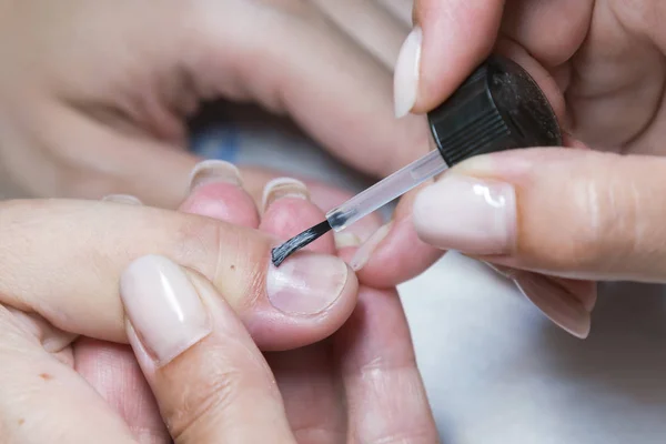 Mujer mano en el tratamiento de manicura con cuchillo de cutícula en el salón de belleza. aplicar un pincel sobre las uñas acrílicas en el salón — Foto de Stock