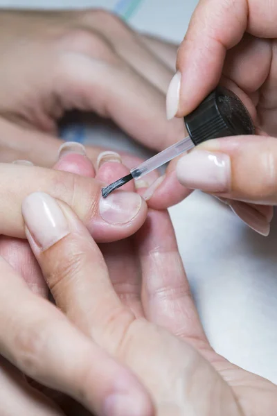 Mujer mano en el tratamiento de manicura con cuchillo de cutícula en el salón de belleza. aplicar un pincel sobre las uñas acrílicas en el salón. foto vertical — Foto de Stock