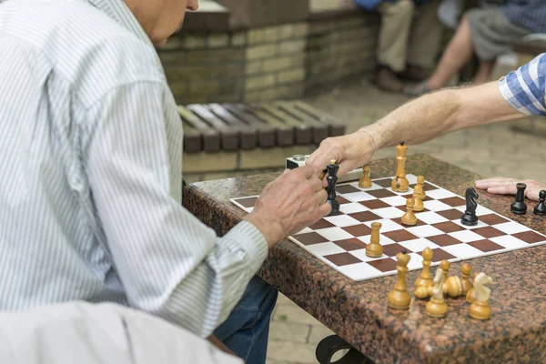 Personas jubiladas activas, viejos amigos y tiempo libre, personas mayores divirtiéndose y jugando al ajedrez en el parque. Cintura para arriba. Viejos jugando ajedrez en el parque — Foto de Stock