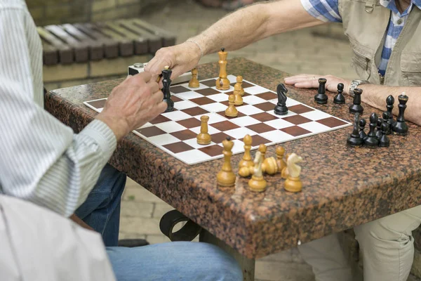 Active retired people, old friends and free time, seniors having fun and playing chess game at park. Waist up. Old men playing chess in the park