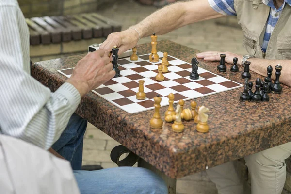 Personas jubiladas activas, viejos amigos y tiempo libre, personas mayores divirtiéndose y jugando al ajedrez en el parque. Cintura para arriba. Viejos jugando ajedrez en el parque — Foto de Stock