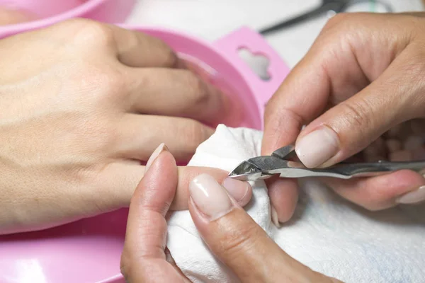 Cerrar la mano de la mujer mientras que el proceso de manicura en la tienda de uñas. Hermoso concepto. procesamiento de manicura de uñas hembra —  Fotos de Stock