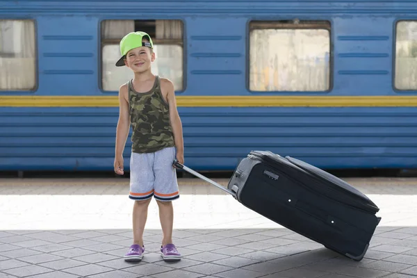 Счастливый Маленький Мальчик Большим Черным Чемоданом Фоне Синего Поезда Концепция — стоковое фото