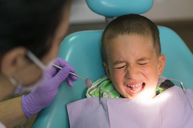 Küçük çocuk diş hekiminde dişçi koltuğunda tedavi görüyor...