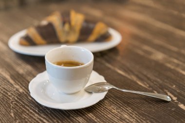 Ahşap arka planda çikolata ve bir fincan kahve ile taze ve lezzetli kruvasan.