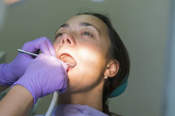 Dentist and patient in dentist office. Close-up of dental drill use for patient teeth in dentistry office in dental treatment procedure.