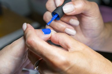 Manikür işlemi. Tırnak cilası yakın plan uygulanıyor..