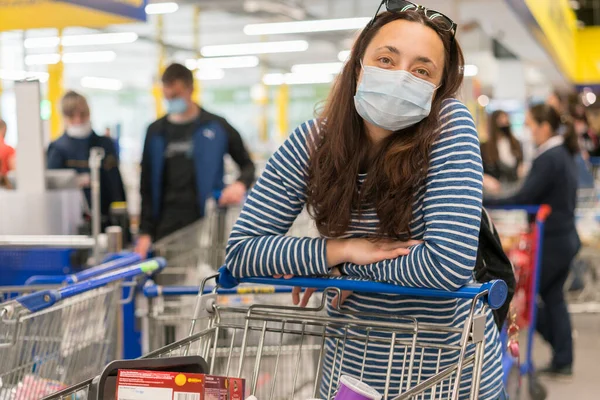 young woman wearing a hygiene protective mask over her face while walking at the crowded shopping mall. Covid19 influenza in crowded place. woman wearing a mask in the supermarket