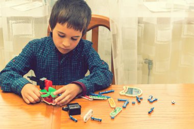 Elektrikli bir inşaatçıyı oynayan çocuk. Çocuk entellektüel oyuncaklar tarafından oynanır. Mavi gömlekli bir çocuk elektronik ustası. Çocukların erken gelişimi kavramı. ses tonlu