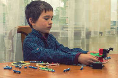 Elektrikli bir inşaatçıyı oynayan çocuk. Çocuk entellektüel oyuncaklar tarafından oynanır. Mavi gömlekli bir çocuk elektronik ustası. Çocukların erken gelişimi kavramı. ses tonlu