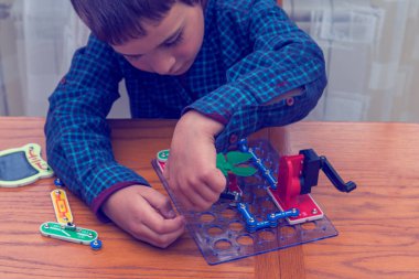Elektrikli bir inşaatçıyı oynayan çocuk. Çocuk entellektüel oyuncaklar tarafından oynanır. Mavi gömlekli bir çocuk elektronik ustası. Çocukların erken gelişimi kavramı. ses tonlu