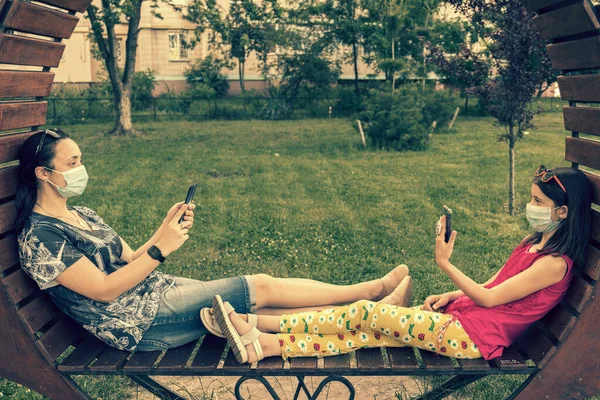 Mom with daughter in the park in medical masks. Family of mom and kid wearing protective medical mask for prevent virus outdoors in the park. new normal concept. toned.