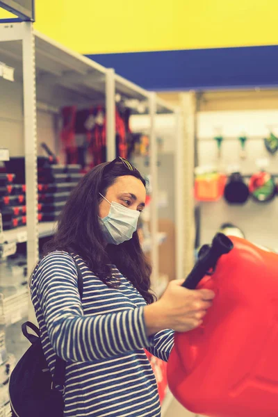 Koruyucu maskeli bir kadın elinde bir kutuyla bir mağazada. Salgın hastalık konsepti. Salgın Alışveriş. Dikey fotoğraf. ses tonlu.
