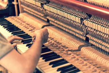 Piyano akort işlemi. Büyük piyanoda çalışan el ve akort aletlerinin yakın çekimi. Akort sırasında Upright Piano 'nun detaylı görüntüsü. ses tonlu