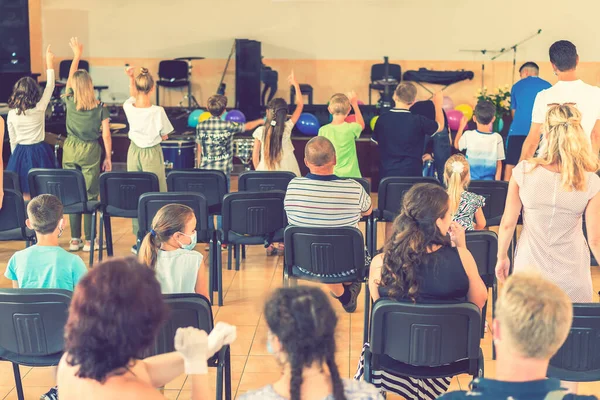 Vacaciones infantiles en la escuela primaria. Los niños en el escenario actúan delante de los padres. imagen de los niños borrosa s muestran en el escenario en la escuela, para el uso de fondo. Borrosa. tonificado — Foto de Stock