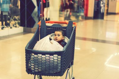 İçinde çocuğun oturduğu bir yük arabası. Süpermarkette yiyecek dolu bir araba. Bebek arabasında bir bebek oturuyor. ses tonlu.