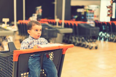 Süpermarketteki el arabasında yeni yürümeye başlayan çocuk. ses tonlu.