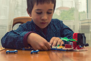 Elektrikli bir inşaatçıyı oynayan çocuk. Çocuk entellektüel oyuncaklar tarafından oynanır. Mavi gömlekli bir çocuk elektronik ustası. Çocukların erken gelişimi kavramı. ses tonlu