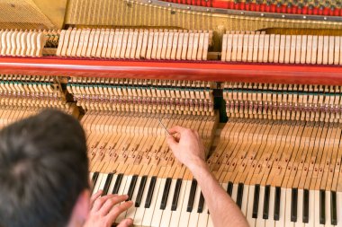 Piyano akort işlemi. Büyük piyanoda çalışan el ve akort aletlerinin yakın çekimi. Akort sırasında Upright Piano 'nun detaylı görüntüsü. ses tonlu.
