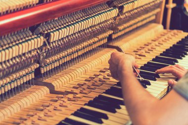 Piyano akort işlemi. Büyük piyanoda çalışan el ve akort aletlerinin yakın çekimi. Akort sırasında Upright Piano 'nun detaylı görüntüsü. ses tonlu.