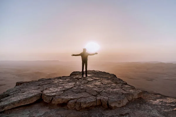 男一人でイスラエルのネゲヴ砂漠日の出の景色を賞賛します。崖の端に立っている若い男性人 — ストック写真