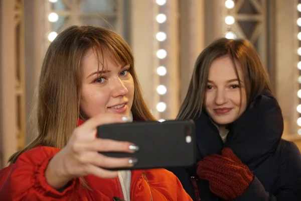 Avrupa Noel piyasasında Smartphone kullanan kadın. Kız zevk kış tatil sezonu, kullanılması telefon, sosyal ağ bulanık Noel ışıkları arka planda, alacakaranlıkta.