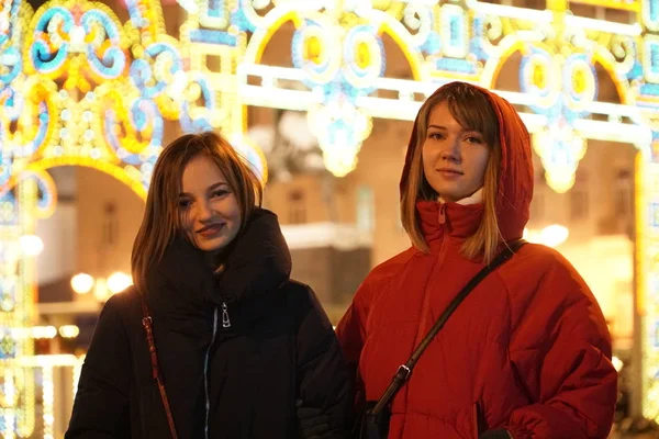 Avrupa Noel piyasasında Smartphone kullanan kadın. 4 k. kız zevk kış tatil sezonu, kullanılması telefon, sosyal ağ, iletişim, uygulama bulanık Noel ışıkları kullanarak arka planda, alacakaranlıkta.
