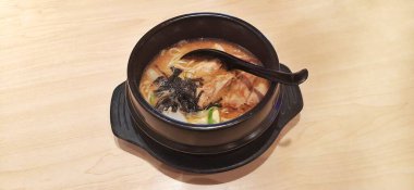 Erişteli erişteli tavuk katsu ve siyah kasede servis edilen malzemeler.