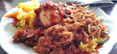 Tahta bir tabakta servis edilen Nasi kuning veya Sarı Pirinç