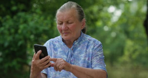 Starší šedovlasá babička si užívá používání mobilní aplikace, starší dáma psaní textových zpráv držet chytrý telefon podívat se na obrazovce mobilního telefonu procházení sociálních médií doma, staří lidé tech uživatelé koncept