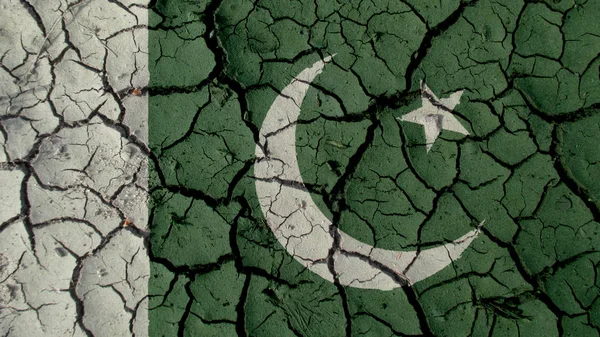 Кризисная концепция: трещины в грязи с флагом Пакистана — стоковое фото