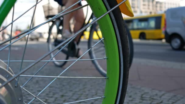 Rueda de radio verde de una bicicleta con tráfico en el fondo, enfoque seleccionado — Vídeos de Stock