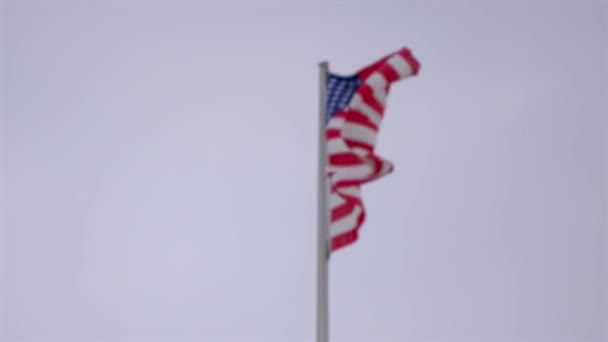 Fondo borroso: Bandera desenfocada de los Estados Unidos en la bandera que ondea en el fuerte viento — Vídeo de stock