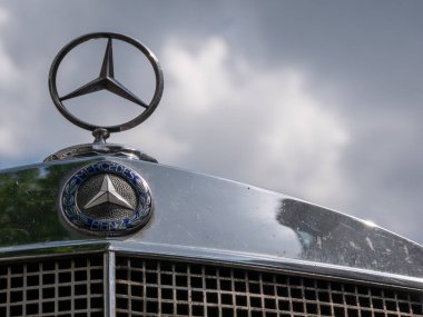 Mercedes logosu ve yıldız bulutlu bir gökyüzüne karşı bir Mercedes vintage araba