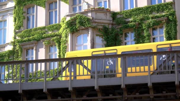 Train de métro jaune BVG U-Bahn devant une maison avec des plantes grimpantes — Video