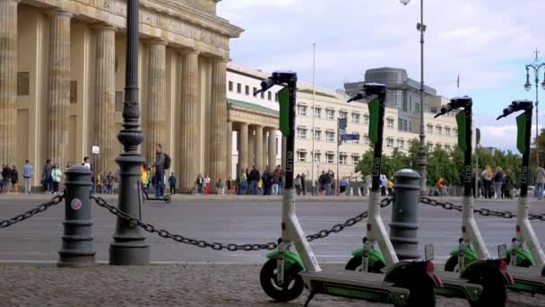 Elektrische kick scooters en een man die een scooter rijdt bij de Brandenburger Tor in Berlijn — Stockvideo