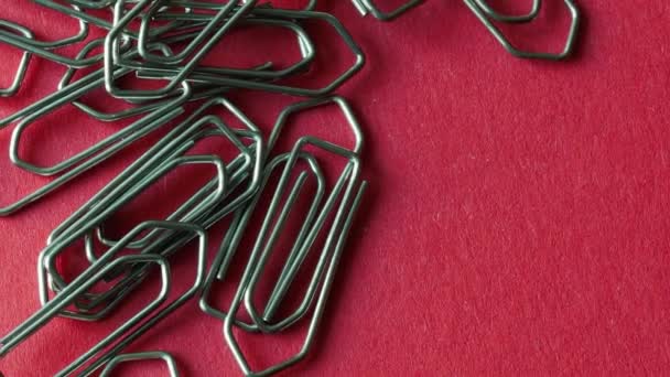 Close-up van glimmende metalen paperclips op rood papier, uitzoomen — Stockvideo