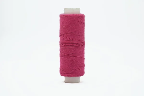 Beyaz bir arka plan üzerinde izole bir dikiş makinesi yakın çekim için pembe iplik uzun plastik skein.