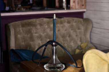 Salon barda kahverengi bir masada berrak su ile mavi ahşap nargile.