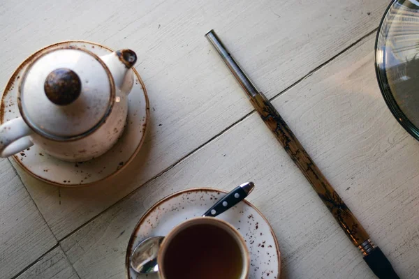 Dinlenme odasındaki masada bir çaydanlığın ve fincanın yanında tahta bir ağızlık. Üst görünüm.