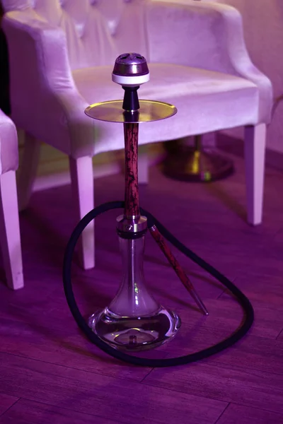 Salon barındaki beyaz koltuğun yanında tahta nargile var..