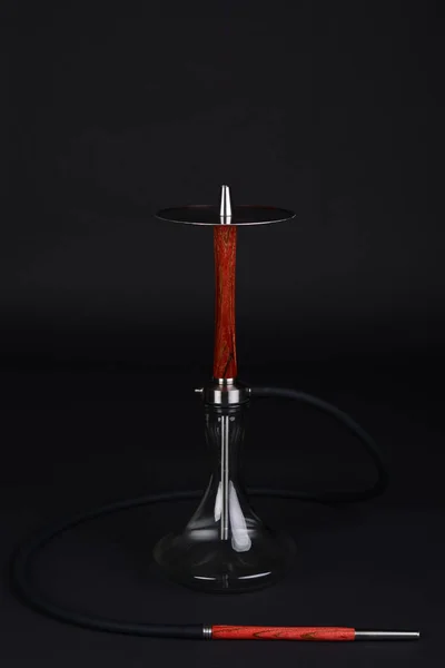 Temiz bir kase ve koyu bir arka plan üzerinde siyah hortum ile kırmızı ahşap nargile.