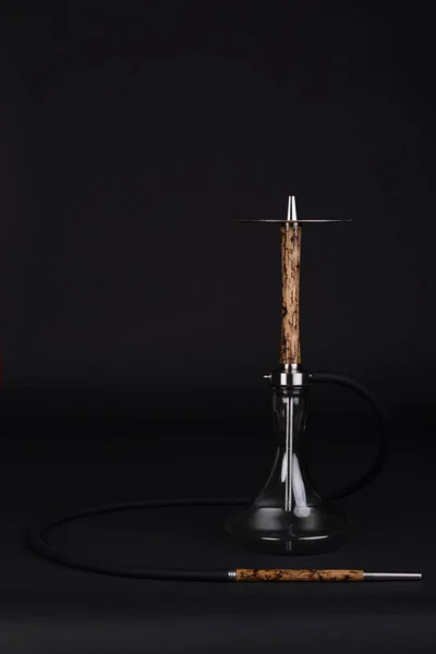 Koyu bir arka plan üzerinde temiz bir kase ve siyah hortum ile Bej ahşap nargile.