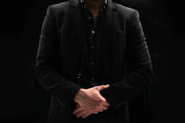 Portrait of a business man in a dark jacket and unbuttoned shirt who folded his arms on a black background. Male does not show face. Royalty Free Stock Images