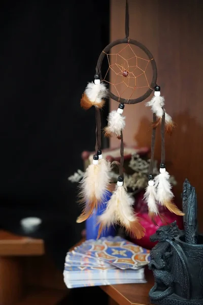 Esoteric items on a wooden shelf. Tarot cards, dream catcher, amulet, black clay dragon. Occult, esoteric, divination and Wicca concept. Mystic and vintage background.