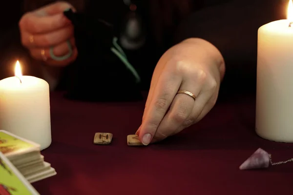 Bruja es adivina en manto negro con un anillo muestran runas antiguas en la mesa. Tarjetas del tarot, piedras de amatista, velas blancas sobre fondo místico oscuro. Concepto oculto, esotérico, adivinación y wicca . — Foto de Stock